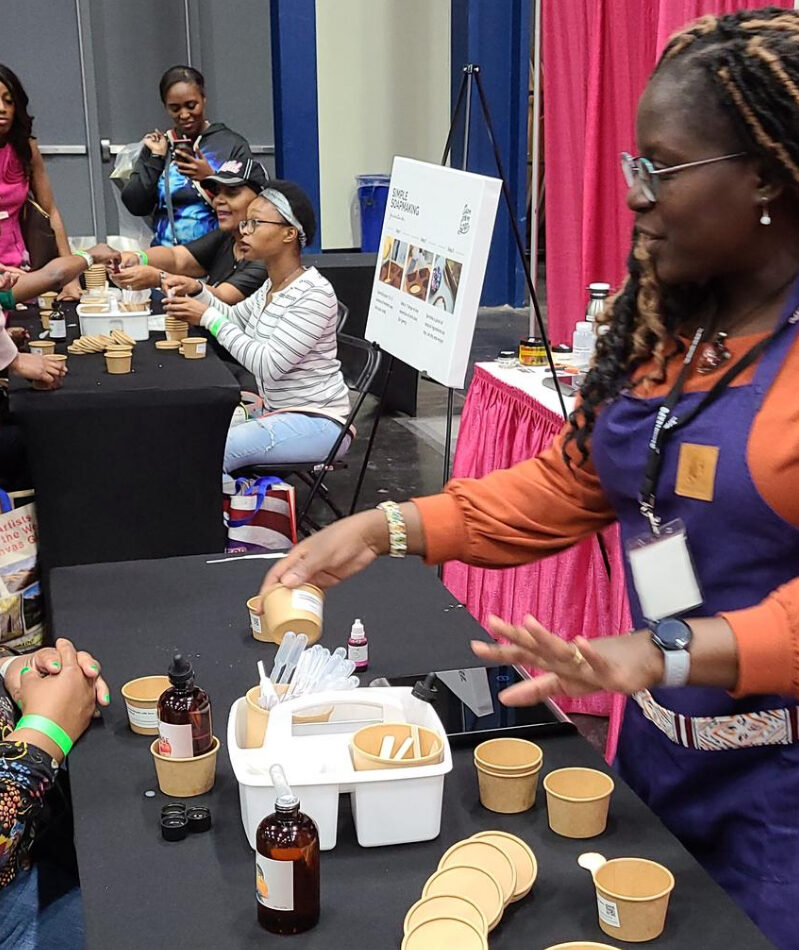 Super Power Soap - team building diy soap making workshop image showing people and paper cups on and around a table at the George R. Brown Convention Center during the Ultimate Women's Expo.