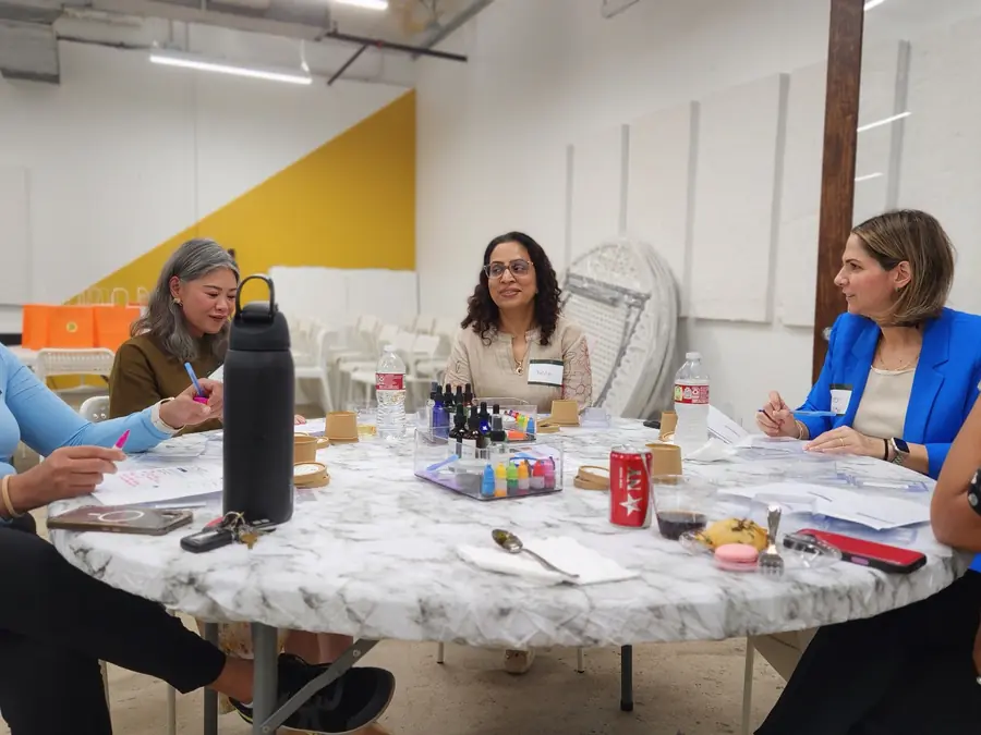 Colleagues gathered around a prepared soapmaking table in a professional event space.